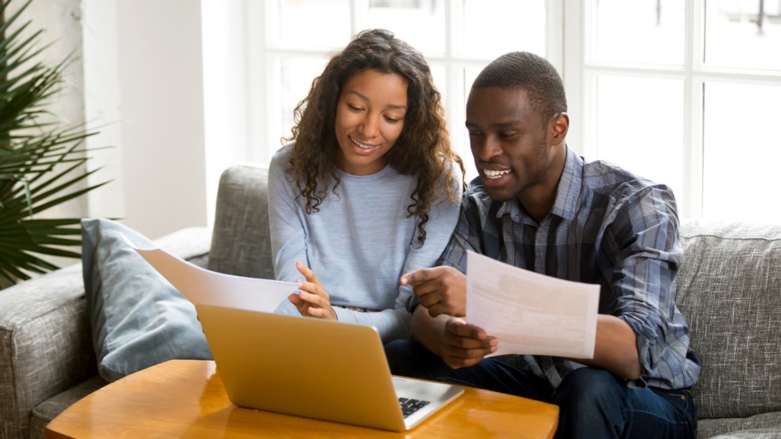 Two people looking at documents with a laptop in front of them | BetterBond