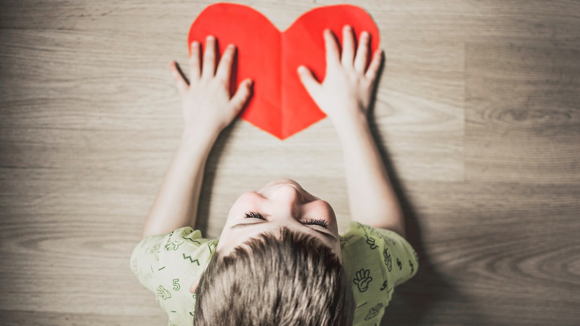 Small child with hands on red heart cutout | BetterBond